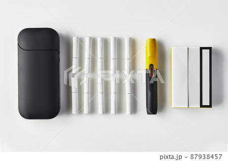 New generation black and yellow electronic cigarette and battery, one pack and ten heatsticks isolated on white. Heating tobacco system. Close up New generation black and yellow electronic cigarette and battery, one pack and ten heatsticks isolated on white. Heating tobacco system. Close up 87938457