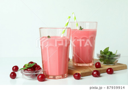 Glasses of cherry smoothie and ingredients on white table Glasses of cherry smoothie and ingredients on white table 87939914