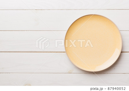 Top view of empty orange plate on wooden background. Empty space for your design 87940052