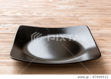 Perspective view of empty square plate on wooden background. Empty space for your design Perspective view of empty square plate on wooden background. Empty space for your design 87940412