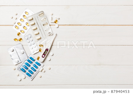 Protective face masks or surgical masks, medicine pills and thermometer on table background. Coronavirus disease. Corona virus concept. Space for text Protective face masks or surgical masks, medicine pills and thermometer on table background. Coronavirus disease. Corona virus concept. Space for text 87940453