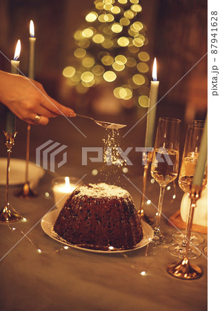 Christmas dinner. Female hand sprinkling sugar powder on pee standing on rustic wooden table 87941628