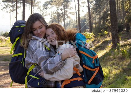 Portrait of two female backpackers embracing Portrait of two female backpackers embracing 87942029