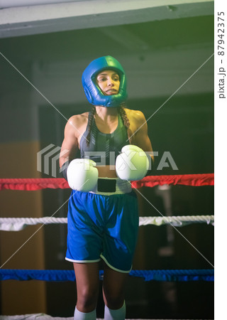 Portrait of serious girl in helmet and gloves on boxing ring 87942375