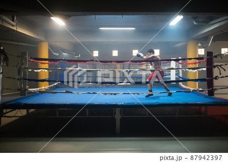 Dedicated man practicing punching technique in ring 87942397