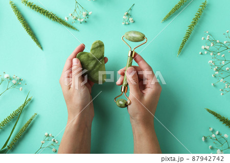 Skin care concept with face roller and gua sha on mint background 87942742