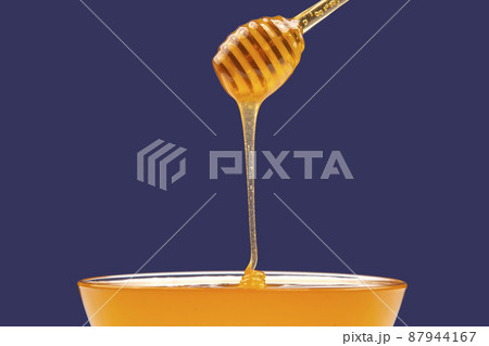 fresh fragrant honey drips from a spoon into a plate on a colored background. 87944167