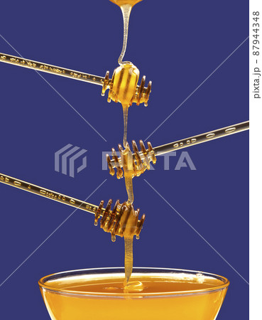 fresh honey drips from a spoon into a plate. organic vitamin health food 87944348