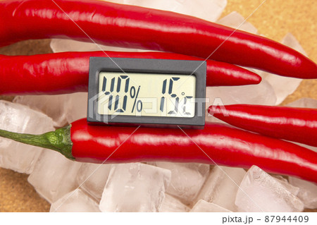 digital thermometer for measuring air temperature and humidity on the background of red hot peppers 87944409