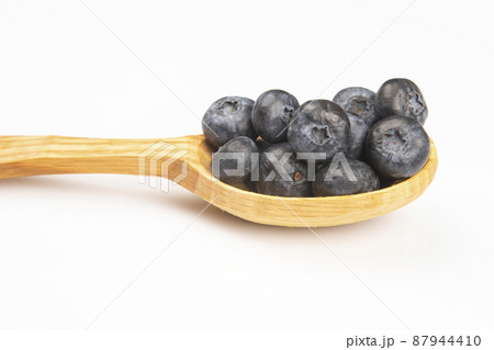 fresh blueberries lie in a wooden spoon on a white background. vitamin organic food fresh blueberries lie in a wooden spoon on a white background. vitamin organic food 87944410