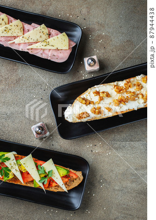 Traditional Spanish breakfast. Tostada with different toppings on a dark background. Top view with copy space Traditional Spanish breakfast. Tostada with different toppings on a dark background. Top view with copy space 87944438