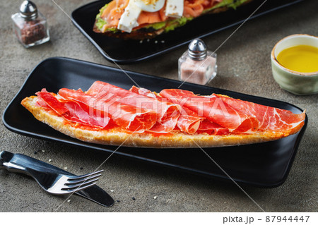 Traditional Spanish breakfast. Tostada with different toppings on a dark background 87944447