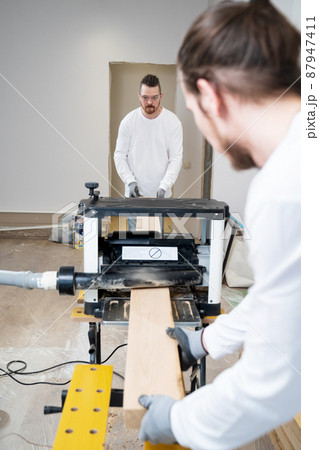carpenters working with wood on the planing machine 87947411