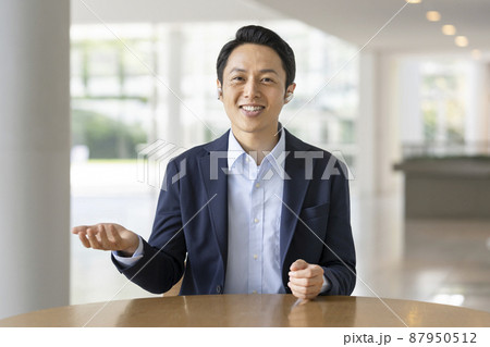 カメラに向かって話すワイヤレスイヤホンをつけた30代のビジネスマン カメラに向かって話すワイヤレスイヤホンをつけた30代のビジネスマン 87950512