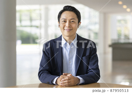 カメラ目線のワイヤレスイヤホンをつけた30代のビジネスマン カメラ目線のワイヤレスイヤホンをつけた30代のビジネスマン 87950513