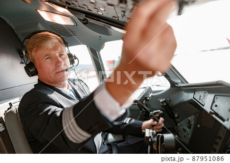 Man pilot in headphones controlling aircraft flight 87951086