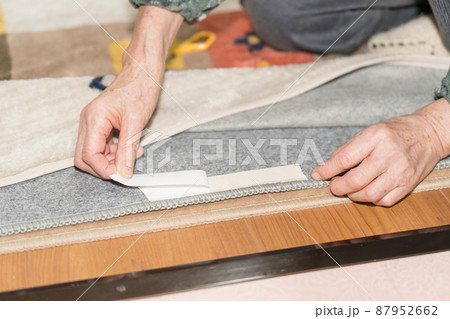 カーペットテープ(両面テープ）を貼るシニア女性 87952662