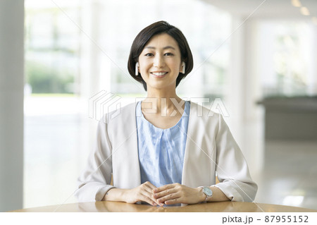 カメラ目線のワイヤレスイヤホンをした笑顔の30代のビジネスウーマン 87955152