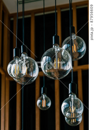 Close up group of beautiful round shape light bulb from ceiling, transparent hanging glass light bulbs for interior decoration, vertical image. 87956609