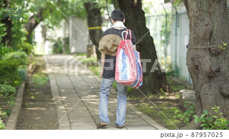 家財道具を持ち歩く男性　後ろ姿 87957025