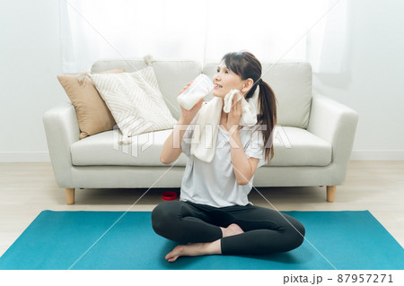 部屋でヨガをするミドル世代の女性(プロテインを飲む) 部屋でヨガをするミドル世代の女性(プロテインを飲む) 87957271