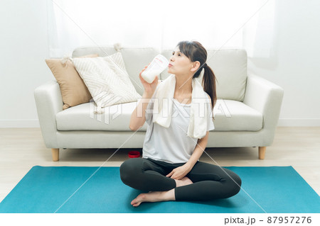 部屋でヨガをするミドル世代の女性(プロテインを飲む) 部屋でヨガをするミドル世代の女性(プロテインを飲む) 87957276