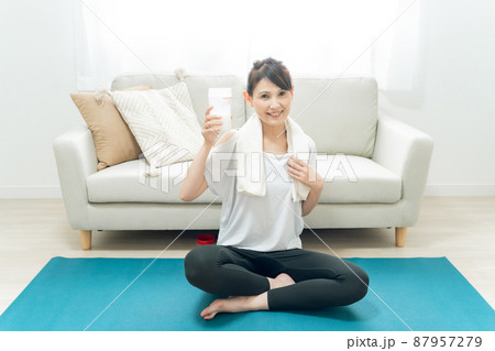 部屋でヨガをするミドル世代の女性(プロテインを飲む) 部屋でヨガをするミドル世代の女性(プロテインを飲む) 87957279