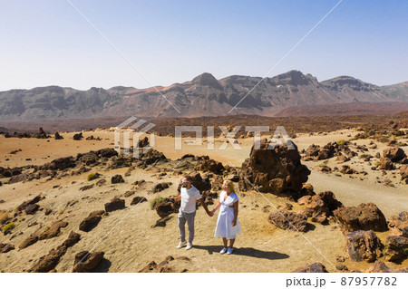 A couple in love stands in the crater of the Teide volcano. Desert landscape in Tenerife. Teide National Park. Tenerife, Spain A couple in love stands in the crater of the Teide volcano. Desert landscape in Tenerife. Teide National Park. Tenerife, Spain 87957782
