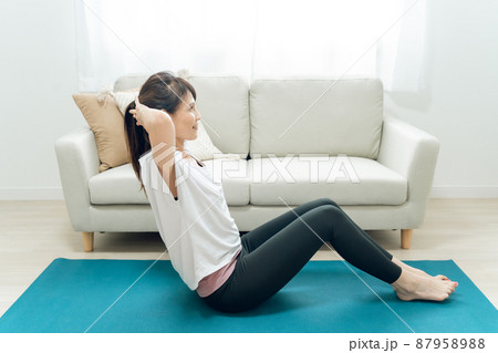 部屋で腹筋をするミドル世代の女性 87958988