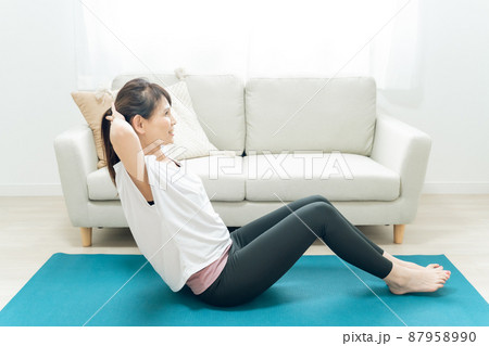 部屋で腹筋をするミドル世代の女性 87958990