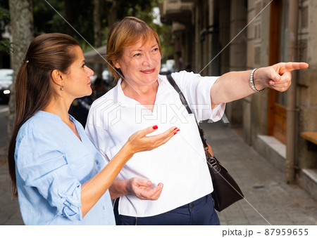 Elderly woman pointing direction to young female Elderly woman pointing direction to young female 87959655