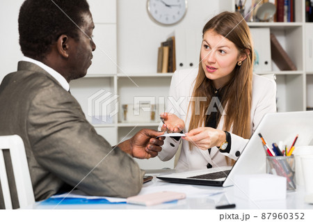 Male and female colleagues working with laptop and talking at table Male and female colleagues working with laptop and talking at table 87960352