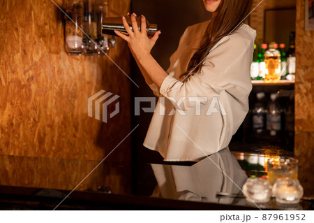 バーカウンターでお酒をつくる女性　BAR 87961952