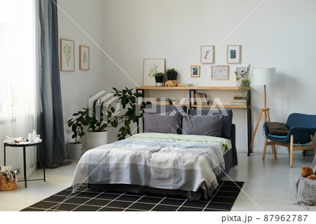 Part of spacious bedroom with double bed and shelves in the center 87962787