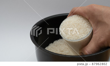計量カップで白米を炊飯ジャーの内釜に入れるシーン 計量カップで白米を炊飯ジャーの内釜に入れるシーン 87962802