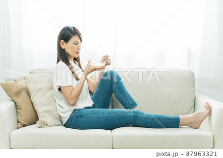 ソファでヨーグルトを食べる女性(困る) ソファでヨーグルトを食べる女性(困る) 87963321