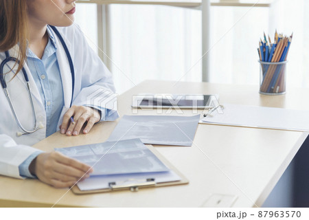 Close up hands of women doctor write prescription medical lab hospital. Crop asian women hand doctors working in medical clinic looking CAT scan xray film. Doctor with stethoscope writing on notepad Close up hands of women doctor write prescription medical lab hospital. Crop asian women hand doctors working in medical clinic looking CAT scan xray film. Doctor with stethoscope writing on notepad 87963570