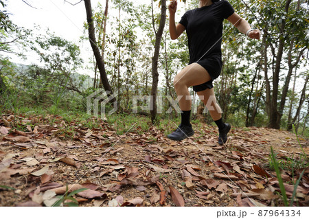 Woman runner running on forest trail Woman runner running on forest trail 87964334