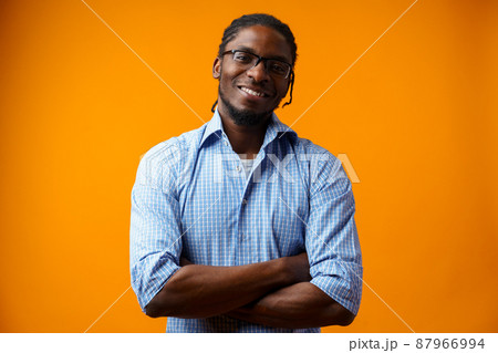 Handsome smiling young african man standing isolated over orange background Handsome smiling young african man standing isolated over orange background 87966994