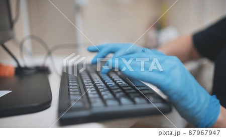 The veterinarian is typing on the keyboard in blue gloves. The veterinarian is typing on the keyboard in blue gloves. 87967947