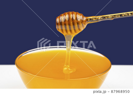 fresh honey dripping from a spoon into a plate on a blue background. organic vitamin health food 87968950