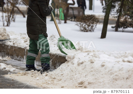 street worker shovels snow from the sidewalk 87970111