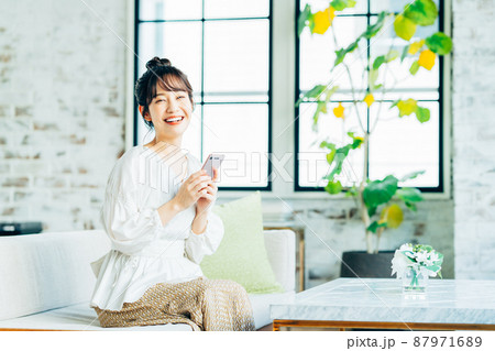 リビングでスマホを見る若い女性 87971689