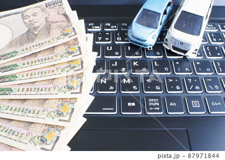 黒いノートパソコンのキーボードと1万円札と水色のコンパクトカーと白いミニバン 87971844