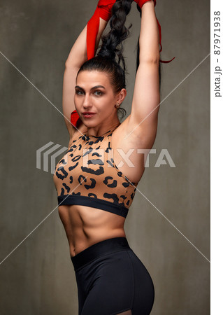 Attractive Young Woman Standing Strong In The Gym And Flexing Muscles - Beautiful Athletic Fitness Model Posing After Exercises. 87971938