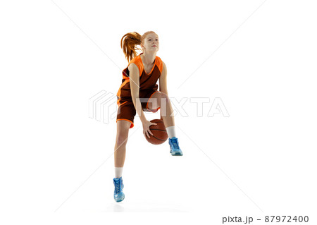 Portrait of young active girl, basketball player in motion, dribblig ball in a jump isolated over white studio background Portrait of young active girl, basketball player in motion, dribblig ball in a jump isolated over white studio background 87972400