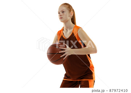 Half-length portrait of young sportive girl, basketball player training, preparing to throw a ball isolated over white studio background 87972410