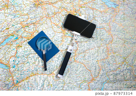 Travel accessories set on the map background: smart, passport and selfish stick. Top view point. Travel accessories set on the map background: smart, passport and selfish stick. Top view point. 87973314