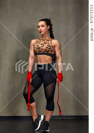 Attractive Young Woman Standing Strong In The Gym And Flexing Muscles - Beautiful Athletic Fitness Model Posing After Exercises. Attractive Young Woman Standing Strong In The Gym And Flexing Muscles - Beautiful Athletic Fitness Model Posing After Exercises. 87973553