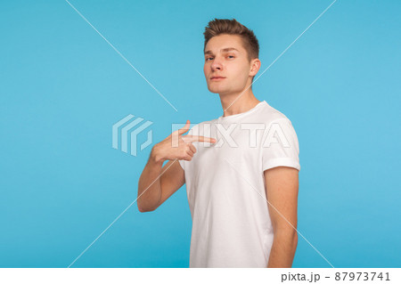 This is me. Portrait of conceited man in t-shirt pointing himself and looking with arrogant selfish expression, feeling successful and self-important. indoor studio shot isolated on blue background 87973741